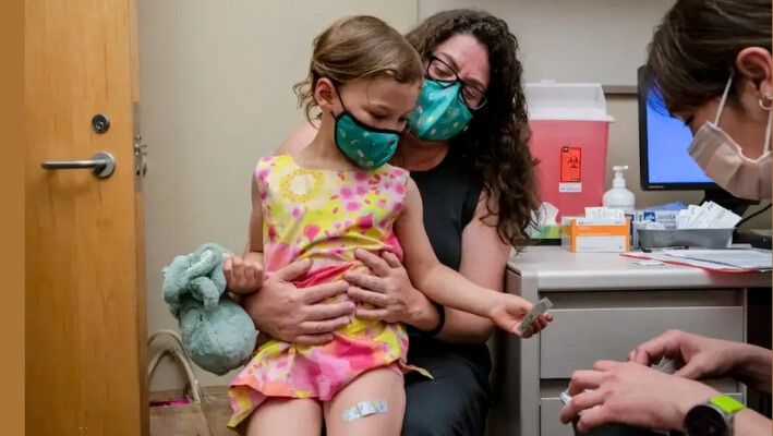 Una niña de 3 años sentada en el regazo de su madre en una foto de archivo durante una vacunación. (David Ryder/Getty Images). 