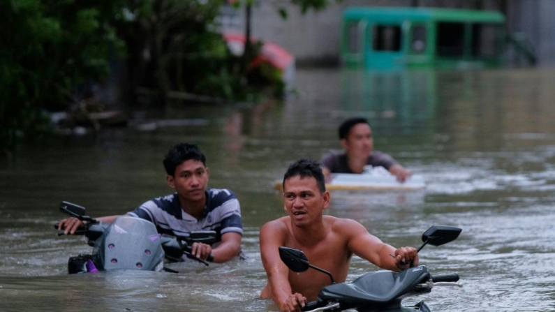 Residentes empujan sus motocicletas a través de una calle inundada causada por las fuertes lluvias provocadas por la tormenta tropical Trami en Naga City, provincia de Camarines Sur (Filipinas) el 24 de octubre de 2024. (Zalrian Sayat/AFP vía Getty Images)