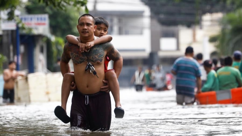 Un hombre lleva a hombros a su hijo el 25 de octubre de 2024 en una calle inundada en la localidad de Cainta, unos 30 kilómetros al este de Manila, tras el paso de la tormenta Trami por el norte de Filipinas. EFE/EPA/Rolex Dela Pena 