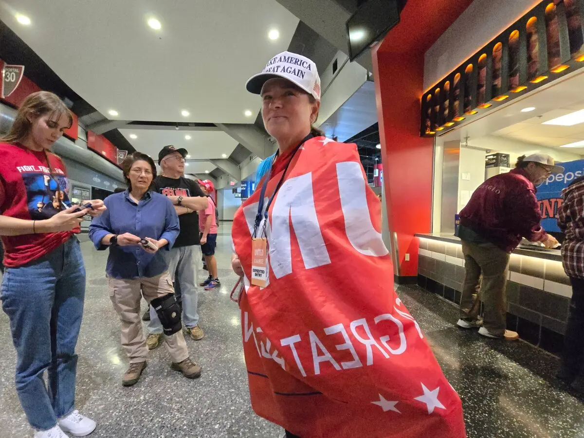 Gina Calabrase cubre con una pancarta de apoyo al expresidente Donald Trump durante un mitin en Las Vegas el 24 de octubre de 2024. (Allan Stein/The Epoch Times)