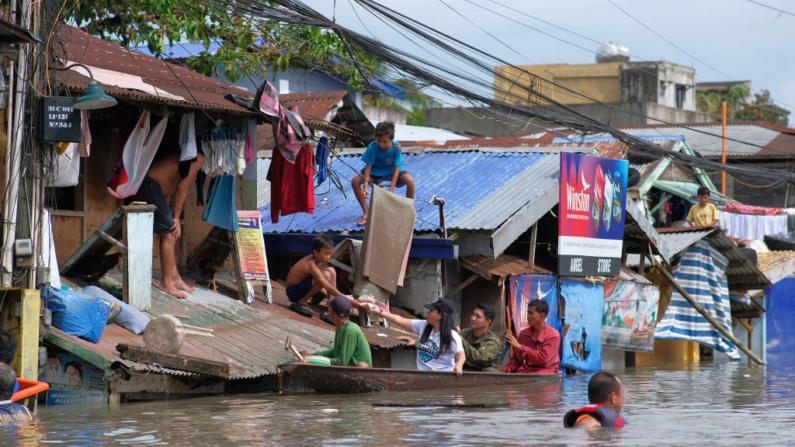 La gente en un barco lleva a cabo operaciones de socorro en una zona inundada debido a las fuertes lluvias provocadas por la tormenta tropical Trami en Naga, Camarines Sur (Filipinas), el 25 de octubre de 2024. (Zalrian Sayat/AFP vía Getty Images)