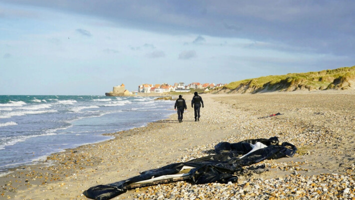 La policía francesa pasa junto a un bote desinflado en la playa de Wimereux, cerca de Calais, Francia, el 18 de noviembre de 2021. (Gareth Fuller/PA).
