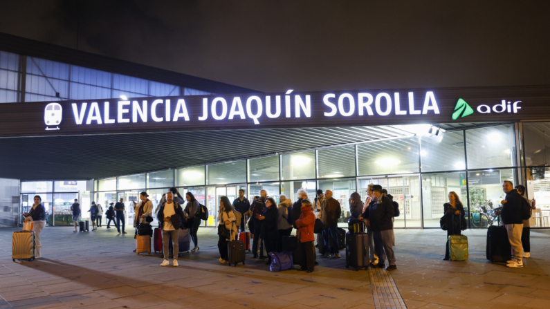 Un grupo de personas aguarda ante la estación Joaquín Sorolla cuando el temporal de lluvias ha obligado a suspender las conexiones de Alta Velocidad entre València y Madrid y afecta a la circulación de cuatro líneas de Cercanías del Núcleo de València, C1, C2, C3 y C6. EFE/Miguel Ángel Polo