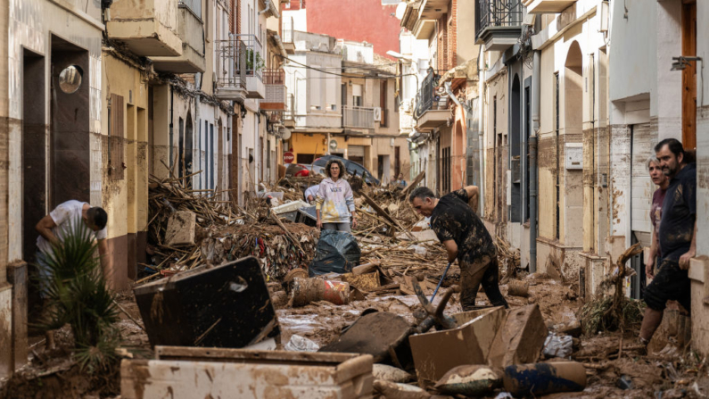 Residentes limpian una calle cubierta de barro y escombros después de que las inundaciones azotaran gran parte del país el 31 de octubre de 2024 en el municipio de Paiporta de Valencia, España. (David Ramos/Getty Images)