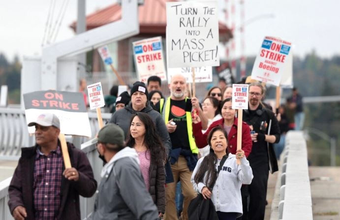 Varias personas portan pancartas mientras marchan hacia Boeing Field tras una concentración de huelga de la Asociación Internacional de Maquinistas y Trabajadores Aeroespaciales (IAM) en el Seattle Union Hall de Seattle el 15 de octubre de 2024. (Jason Redmond/AFP vía Getty Images)