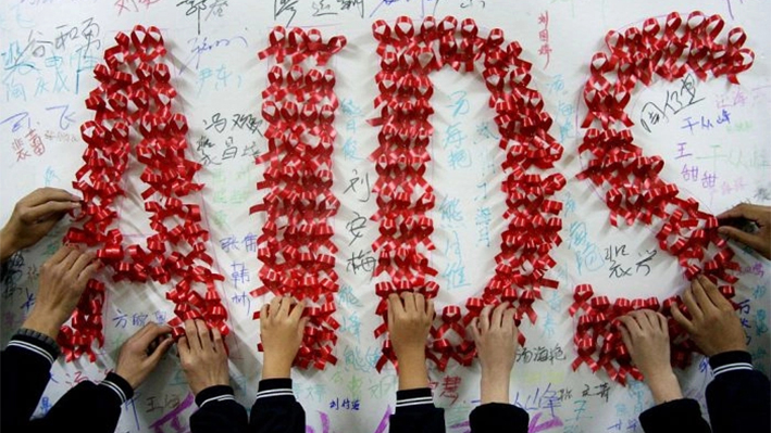 Estudiantes chinos utilizan cintas rojas hechas a mano para formar la palabra "SIDA" un día antes del Día Mundial del SIDA, en una escuela de Hanshan, provincia oriental china de Anhui, el 30 de noviembre de 2009. (STR/AFP/Getty Images)