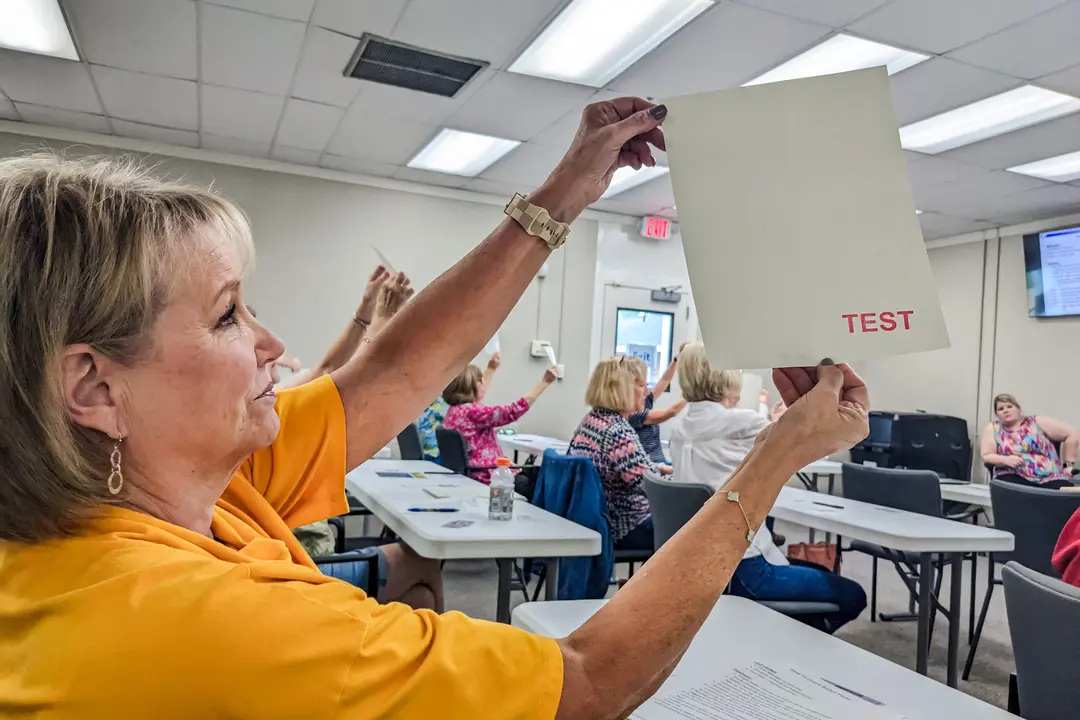 Trabajadores electorales del condado de Lee buscan marcas de agua en el papel de votación durante la formación de trabajadores electorales en Leesburg, Georgia, el 2 de octubre de 2024. (Becca Milfeld/AFP vía Getty Images)