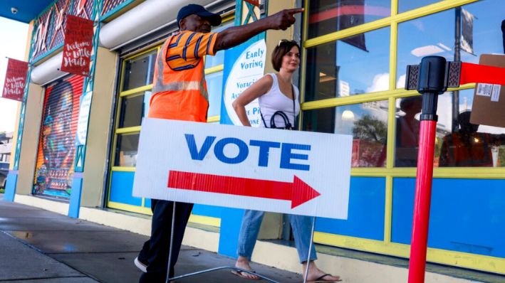 Un trabajador electoral dirige a un votante a un colegio electoral establecido dentro del Complejo Cultural Little Haiti mientras comienza la votación anticipada en Miami, Florida, en octubre. 21, 2024. (Joe Raedle/Getty Images)