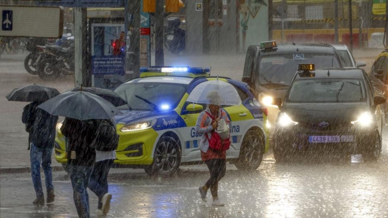 Varias personas se protegen de la lluvia en la Plaza de Espanya de Barcelona el 4 de noviembre de 2024 cuando las comarcas de del Garraf y del Barcelonès, en Barcelona, están en aviso rojo de la Agencia Estatal de Meteorología (Aemet), y la Generalitat ha enviado una alerta a los teléfonos móviles por la llegada de lluvias continuadas y torrenciales. EFE/Quique García