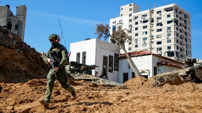 Un soldado israelí corre por un agujero similar a un cráter que da paso a la entrada de un túnel, que conduce al lugar donde los militares descubrieron túneles debajo de la sede principal de UNRWA, la agencia de la ONU para los refugiados palestinos, en Gaza, el 8 de febrero de 2024. (AP Photo/Ariel Schalit)