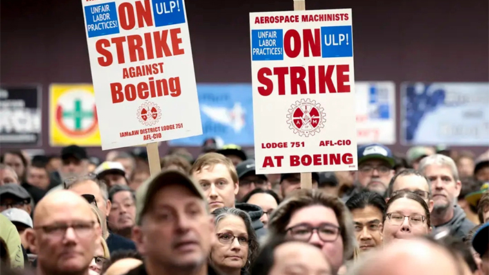 Un grupo de personas sostiene pancartas durante una concentración de huelga de la Asociación Internacional de Maquinistas y Trabajadores Aeroespaciales (IAM) en el Seattle Union Hall de Seattle el 15 de octubre de 2024. (Jason Redmond/AFP vía Getty Images)