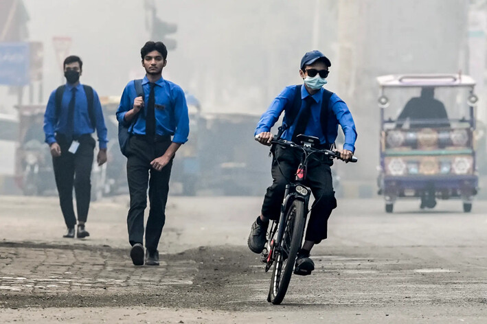 Un estudiante con mascarilla se dirige a la escuela en bicicleta por una calle envuelta en smog, en Lahore, Pakistán, el 5 de noviembre de 2024. (Arif Ali/AFP vía Getty Images)