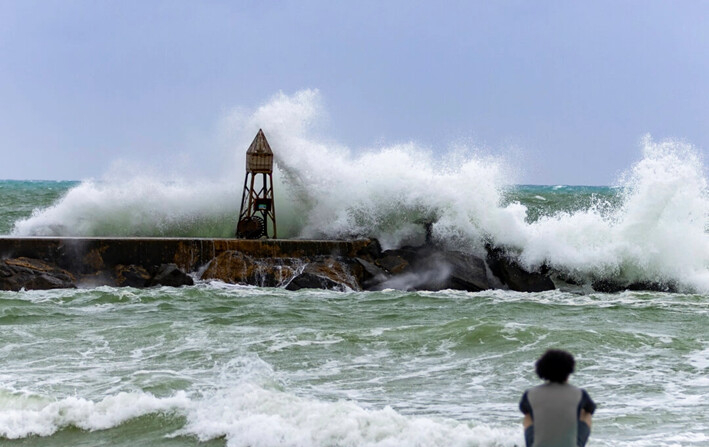 Un surfista observa las olas rompiendo contra el embarcadero del faro de Bal Harbour, en Bal Harbour, Florida, el 5 de noviembre de 2024. (David Santiago/Miami Herald vía AP)