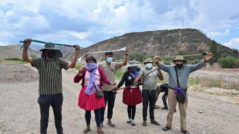 Hombres y mujeres indígenas partidarios del expresidente Evo Morales sostienen una huaraca (una honda hecha de lana para arrojar piedras) durante un entrenamiento sobre su uso en un bloqueo de carreteras en Parotani, a 40 kilómetros de Cochabamba, Bolivia, el 31 de octubre de 2024. (Aizar Raldes/AFP vía Getty Images)