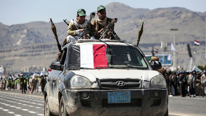 Combatientes leales a los hutís de Yemen se sientan con ametralladoras pesadas encima de un vehículo con otros combatientes en el interior que llevan lanzagranadas propulsadas por cohetes (RPG)durante un desfile militar que marca el aniversario de la toma de la capital Sanaa por los hutís en 2014 y en solidaridad con el pueblo palestino, en Sanaa el 21 de septiembre de 2024. (OSAMA ABDULRAHMAN/AFP vía Getty Images)