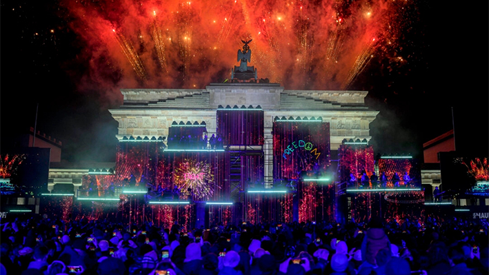 Fuegos artificiales iluminan el cielo mientras los músicos tocan en el escenario durante el concierto por la libertad con motivo del 35 aniversario de la caída del Muro de Berlín, en Berlín, Alemania, el 9 de noviembre de 2024. (Ebrahim Noroozi/Foto AP)