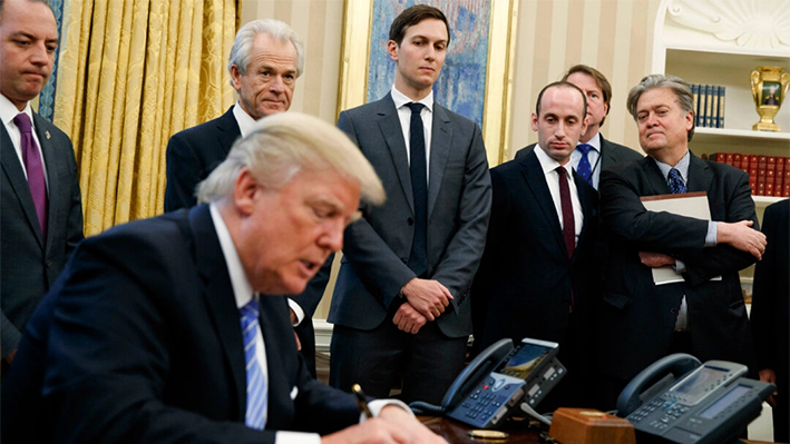 El entonces jefe de gabinete de la Casa Blanca Reince Priebus, el entonces asesor del Consejo Nacional de Comercio Peter Navarro, el entonces asesor principal Jared Kushner, el entonces asesor político Stephen Miller y el entonces estratega jefe Steve Bannon observan cómo el expresidente Donald Trump firma una orden ejecutiva en el Despacho Oval de la Casa Blanca en Washington el 23 de enero de 2017. (AP Photo/Evan Vucci)