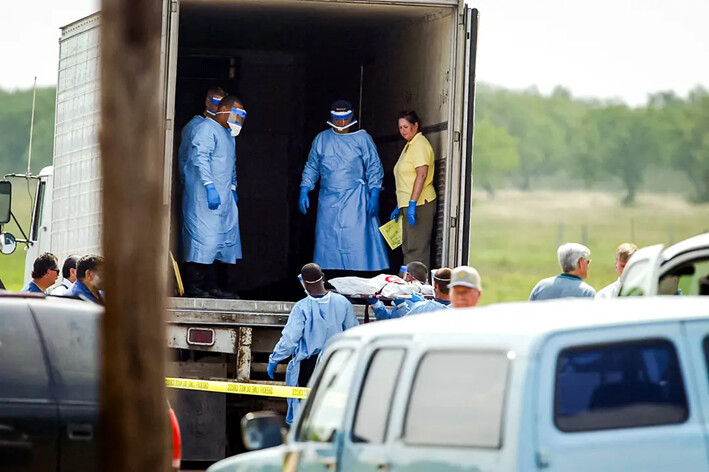 Miembros del cuerpo de bomberos de Victoria trasladan cadáveres de inmigrantes ilegales desde un remolque después de que murieran asfixiados durante su travesía, en Victoria, Texas, el 14 de mayo de 2003. (James Nielsen/AFP vía Getty Images)