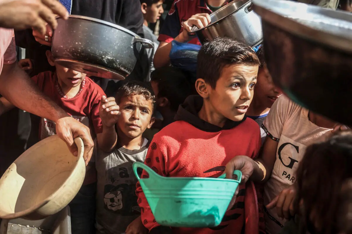 Niños palestinos recogen alimentos de ayuda en el campo de refugiados de Bureij, en el centro de la Franja de Gaza, el 6 de noviembre de 2024. (Eyad Baba/Getty Images)