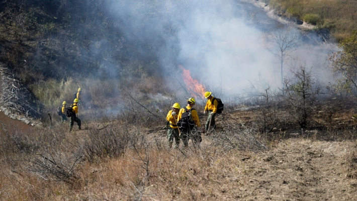 Soldados y aviadores de la Guardia Nacional de Dakota del Norte trabajan con el Departamento de Servicios de Emergencia para construir una línea de mano y llevar a cabo una quema controlada para evitar una mayor propagación de un incendio forestal en Mandaree, Dakota del Norte, el 6 de octubre de 2024. (Sargento Samuel J. Kroll/Guardia Nacional del Ejército de EE.UU. vía AP)