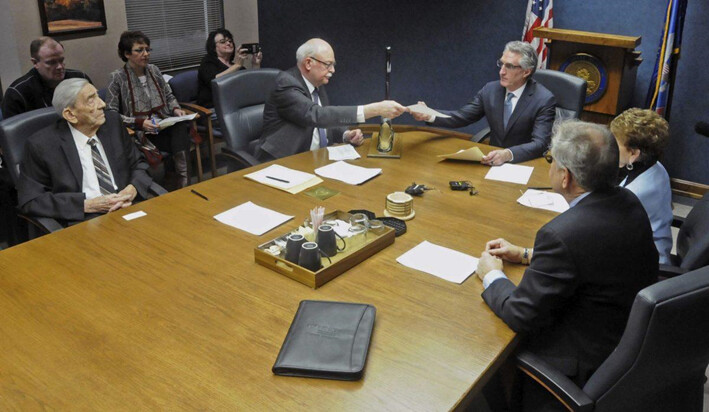 El secretario de Estado de Dakota del Norte, Al Jaeger (izq.), entrega al gobernador Doug Burgum (centro) los resultados de la votación del Colegio Electoral de Dakota del Norte en Bismarck, Dakota del Norte, el 19 de diciembre de 2016. (Tom Stromme/The Bismarck Tribune vía AP)