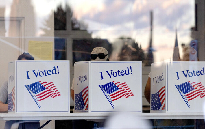 La gente completa sus boletas mientras el atardecer se refleja en el vidrio de un recinto electoral en el vecindario de Bloomfield, en Pittsburgh, Pensilvania, el 5 de noviembre de 2024. (REBECCA DROKE/AFP vía Getty Images)