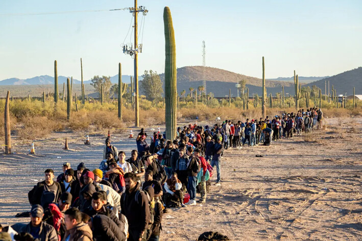 Inmigrantes ilegales hacen fila en un remoto centro de procesamiento de la Patrulla Fronteriza de Estados Unidos después de cruzar la frontera entre Estados Unidos y México, en Lukeville, Arizona, el 7 de diciembre de 2023. (John Moore/Getty Images)