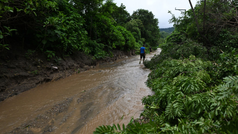 Un hombre camina por una calle inundada después de fuertes lluvias en Santiago Texacuangos, El Salvador, el 21 de junio de 2024. (Marvin Recinos/AFP vía Getty Images)