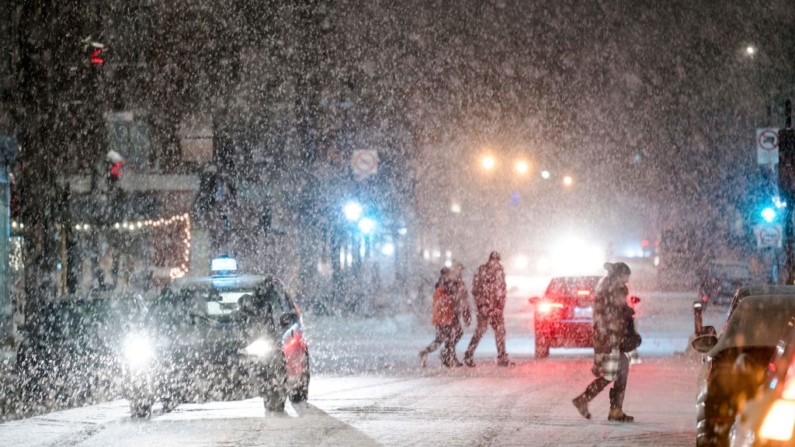 La gente cruza una calle mientras cae la nieve el 22 de diciembre de 2022 en Canadá. (Andrej Ivanov/AFP vía Getty Images)