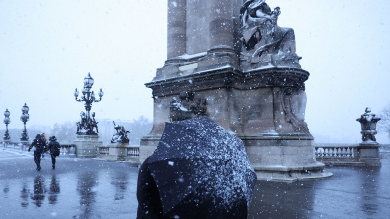 Un hombre sostiene un paraguas mientras camina a lo largo del puente Alexandre III en medio de fuertes nevadas mientras París se encuentra bajo la segunda advertencia meteorológica más alta del servicio meteorológico nacional francés por nieve, en el centro de París el 21 de noviembre de 2024. (Grégoire Campione/AFP vía Getty Images)