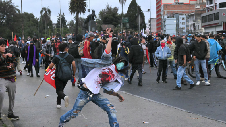 Un manifestante lanza un ladrillo a agentes de la policía antidisturbios durante una protesta convocada por sindicatos y organizaciones sociales contra el gobierno de Daniel Noboa en el centro de Quito (Ecuador), el 21 de noviembre de 2024. (Rodrigo Buendia/AFP vía Getty Images)