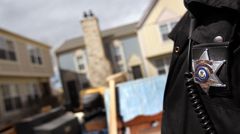 Un ayudante del sheriff revisa las pertenencias de una familia apiladas en el patio delantero de un apartamento después de que fueron retiradas por un equipo de desalojo el 6 de abril de 2010 en Aurora, Colorado. (John Moore/Getty Images)
