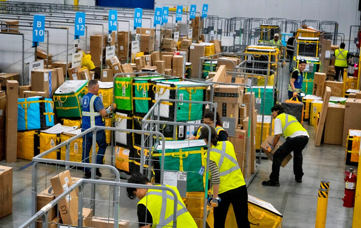 Empleados de Amazon cargan paquetes en carros antes de colocarlos en camiones para su distribución en el evento anual Prime Day de Amazon en una estación de entrega DAX7 de Amazon, en South Gate, California, el 16 de julio de 2024. (Richard Vogel/AP Photo)