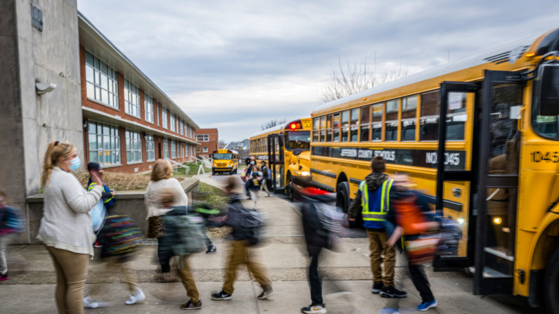 Una profesora saluda a sus alumnos mientras bajan del autobús en la Escuela Primaria Tradicional Carter en Louisville, Kentucky, el 24 de enero de 2022. (Jon Cherry/Getty Images)