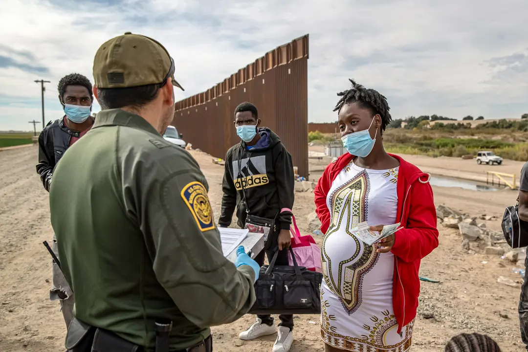 Inmigrantes ilegales, incluida una mujer haitiana embarazada que busca dar a luz en Estados Unidos, son detenidos por un agente de la Patrulla Fronteriza de Estados Unidos en Yuma, Arizona, el 7 de diciembre de 2021. (John Moore/Getty Images)