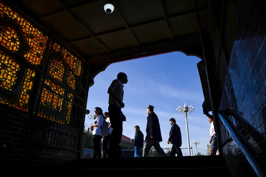 Hombres uigures caminan junto a la salida de un paso subterráneo en Kashgar, en la región china de Xinjiang, el 5 de junio de 2019. (Greg Baker/AFP vía Getty Images)