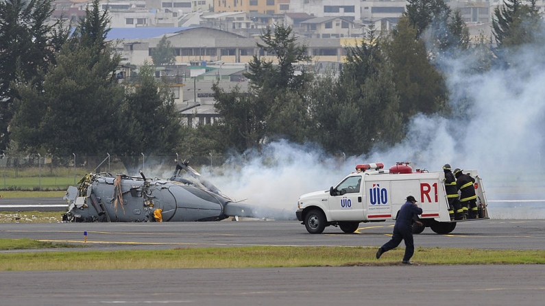 Los bomberos corrieron hacia un helicóptero unos segundos después de que se estrellara durante una exhibición en la base de la Fuerza Aérea Ecuatoriana en Quito el 27 de octubre de 2009. (Rodrigo Buendia/AFP vía Getty Images)