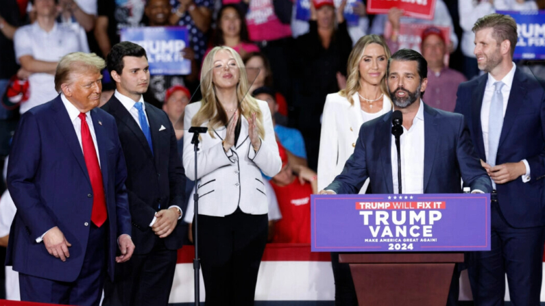 Donald Trump Jr. habla mientras el expresidente estadounidense y candidato presidencial republicano Donald Trump (izq.) escucha junto al cónyuge de Tiffany Trump, Michael Boulos (2º izq.), Tiffany Trump (3º izq.), la copresidenta del Comité Nacional Republicano Lara Trump (3º dcha.) y Eric Trump (dcha.), durante un mitin de campaña en el Van Andel Arena de Grand Rapids, Michigan, el 5 de noviembre de 2024. (Kamil Krzaczynski/AFP vía Getty Images)