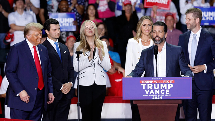 Donald Trump Jr. habla mientras el expresidente y candidato presidencial republicano Donald Trump (izq.) escucha junto al cónyuge de Tiffany Trump, Michael Boulos (segundo izq.), Tiffany Trump (tercera izq.), la copresidenta del Comité Nacional Republicano Lara Trump (tercera der.) y Eric Trump (der.), durante un mitin de campaña en el Van Andel Arena de Grand Rapids, Michigan, el 5 de noviembre de 2024. (Kamil Krzaczynski/AFP vía Getty Images)