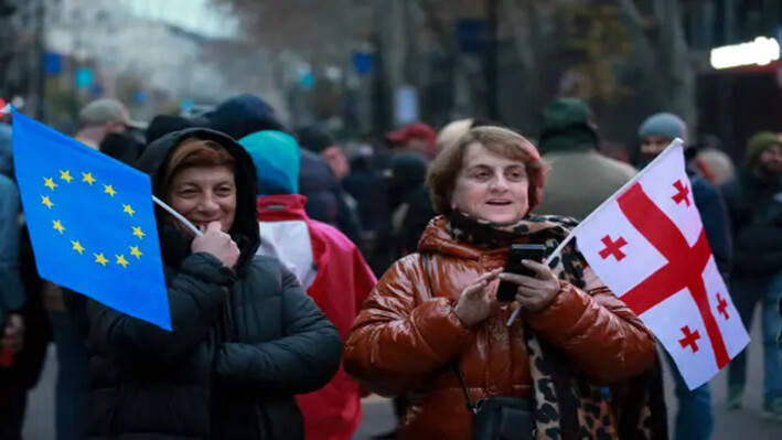 Dos mujeres sostienen una bandera de la UE y una bandera nacional de Georgia durante una protesta frente al edificio del parlamento en Tbilisi, Georgia, el 1 de diciembre de 2024. (Zurab Tsertsvadze/AP)