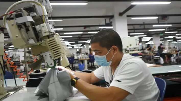 Un trabajador con mascarilla mientras trabaja en la fábrica Maxport, que fabrica ropa deportiva para varias marcas de ropa, en Hanói, Vietnam, el 21 de septiembre de 2021. (Nhac Nguyen/AFP vía Getty Images)