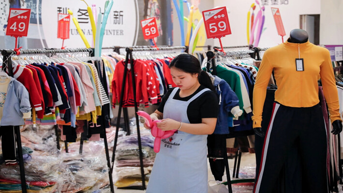 Una empleada usa globos para atraer clientes en una tienda de moda que realiza una promoción en un centro comercial en Shenzhen, provincia de Guangdong, China, el 1 de noviembre de 2019. (Andy Wong/AP)