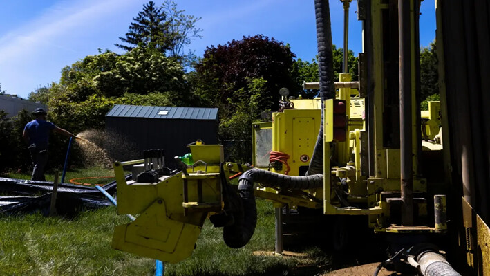 Un empleado de Dandelion Energy riega el exceso de agua subterránea sobre el césped durante la instalación de un sistema de bomba de calor geotérmica en una vivienda de White Plains, Nueva York, el 8 de mayo de 2023. (Julia Nikhinson/Foto AP)