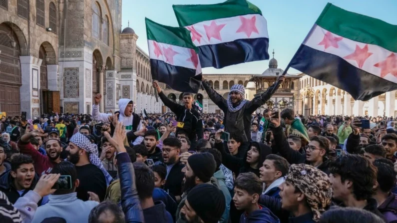 Sirios corean consignas y ondean la nueva bandera de Siria mientras se reúnen en la mezquita Omeya en Damasco, Siria, el 13 de diciembre de 2024. (Leo Correa/AP)







