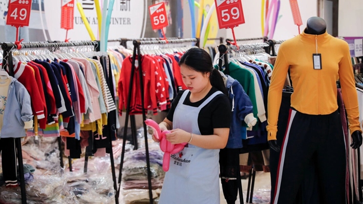 Un empleado usa globos para atraer clientes en una tienda de moda que realiza una promoción en un centro comercial en Shenzhen, provincia de Guangdong, China, el 1 de noviembre de 2019. (Andy Wong/AP)