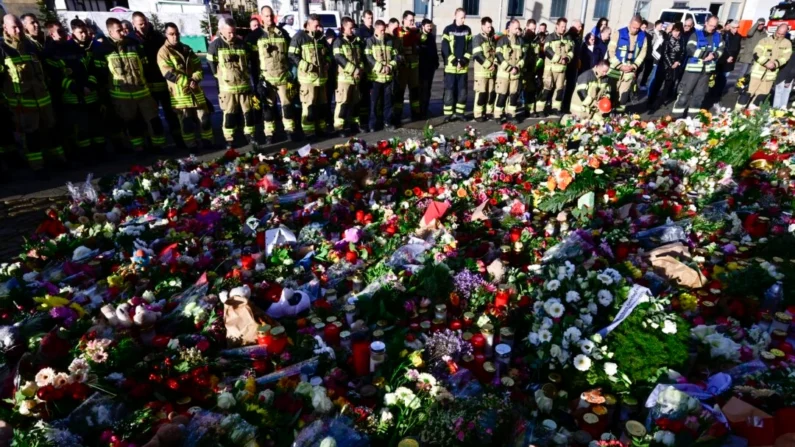 Bomberos de Magdeburgo junto a un monumento improvisado en el exterior de la Johanniskirche (Iglesia de Johannes), cerca del lugar donde se produjo el atentado de la embestida de un auto contra un mercado navideño en Magdeburgo, este de Alemania, el 22 de diciembre de 2024. John MacDougall/AFP vía Getty Images