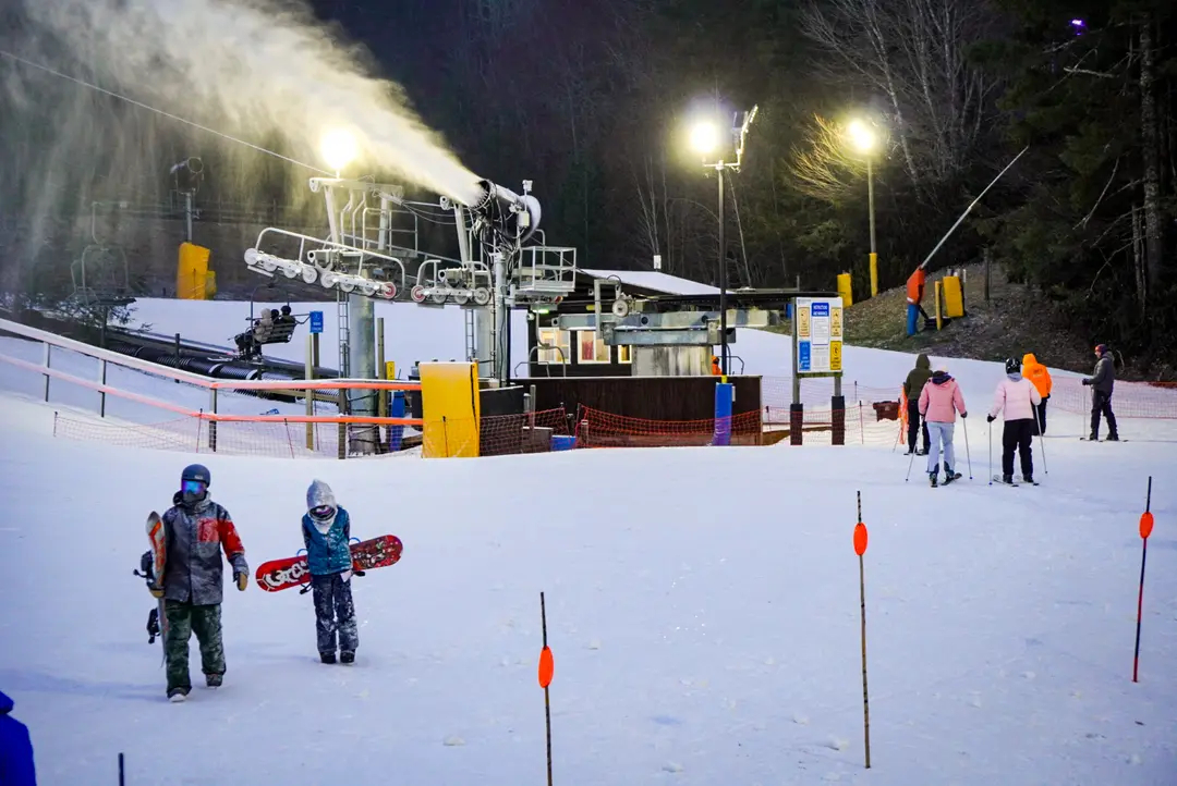 Derek Worthington, residente de Atlanta, y su hijo Ryder (abajo a la izquierda) caminan de regreso al refugio tras un día de snowboard en la estación de esquí de Cataloochee el 11 de diciembre de 2024. (T.J. Muscaro/The Epoch Times)