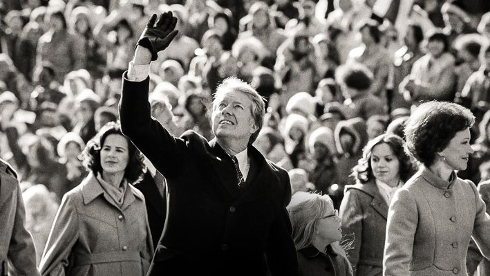 El presidente Jimmy Carter saluda a la multitud mientras camina con su esposa, Rosalynn, y su hija, Amy, por la Avenida Pensilvania desde el Capitolio de Estados Unidos hasta la Casa Blanca después de su toma de posesión, el 20 de enero de 1977. (Suzanne Vlamis, Archivo/Foto AP)