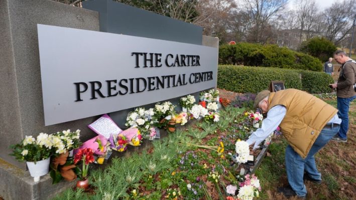 Tom Chaffin, de Atlanta, deja flores en la entrada del Centro Presidencial Jimmy Carter en Atlanta, el 31 de diciembre de 2024. Carter murió el domingo a los 100 años. (AP Photo/John Bazemore)