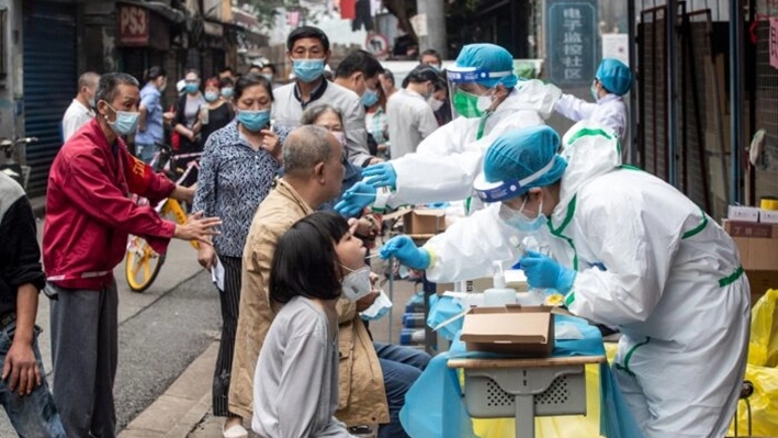 Trabajadores médicos toman muestras de hisopado de los residentes para realizarles la prueba del coronavirus COVID-19, en una calle de Wuhan, en la provincia central china de Hubei, el 15 de mayo de 2020. (STR/AFP vía Getty Images)